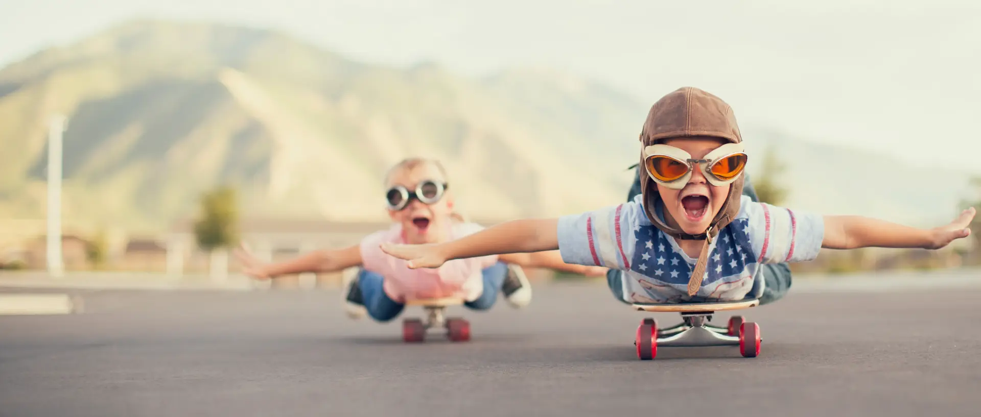 Glückliche Kinder fahren auf dem Bauch liegend Skateboard