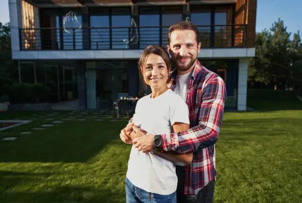 Bärtiger gutaussehender Mann umarmt seine Freundin vor dem modernen Haus