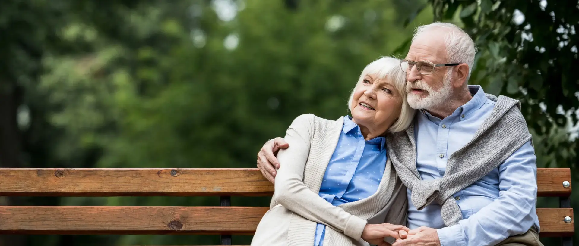 Rentnerpaar sitzt auf einer Bank im Park und geniesst ihre freie Zeit