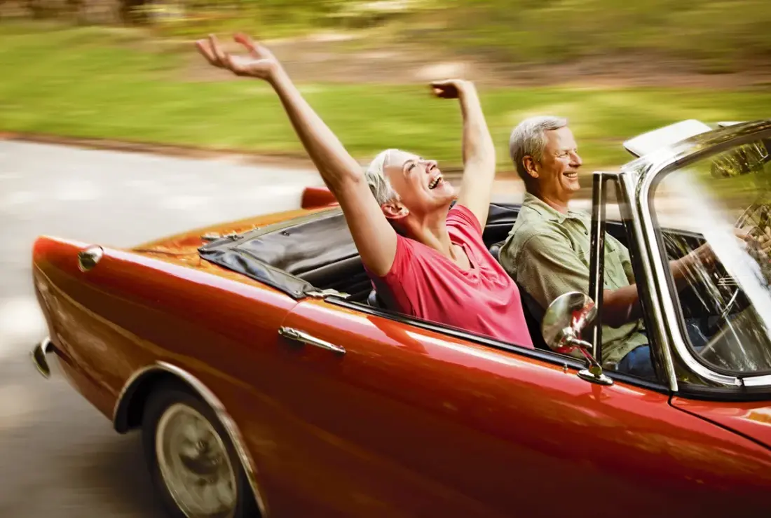 Zwei lebensfrohe Senioren fahren im Cabrio 