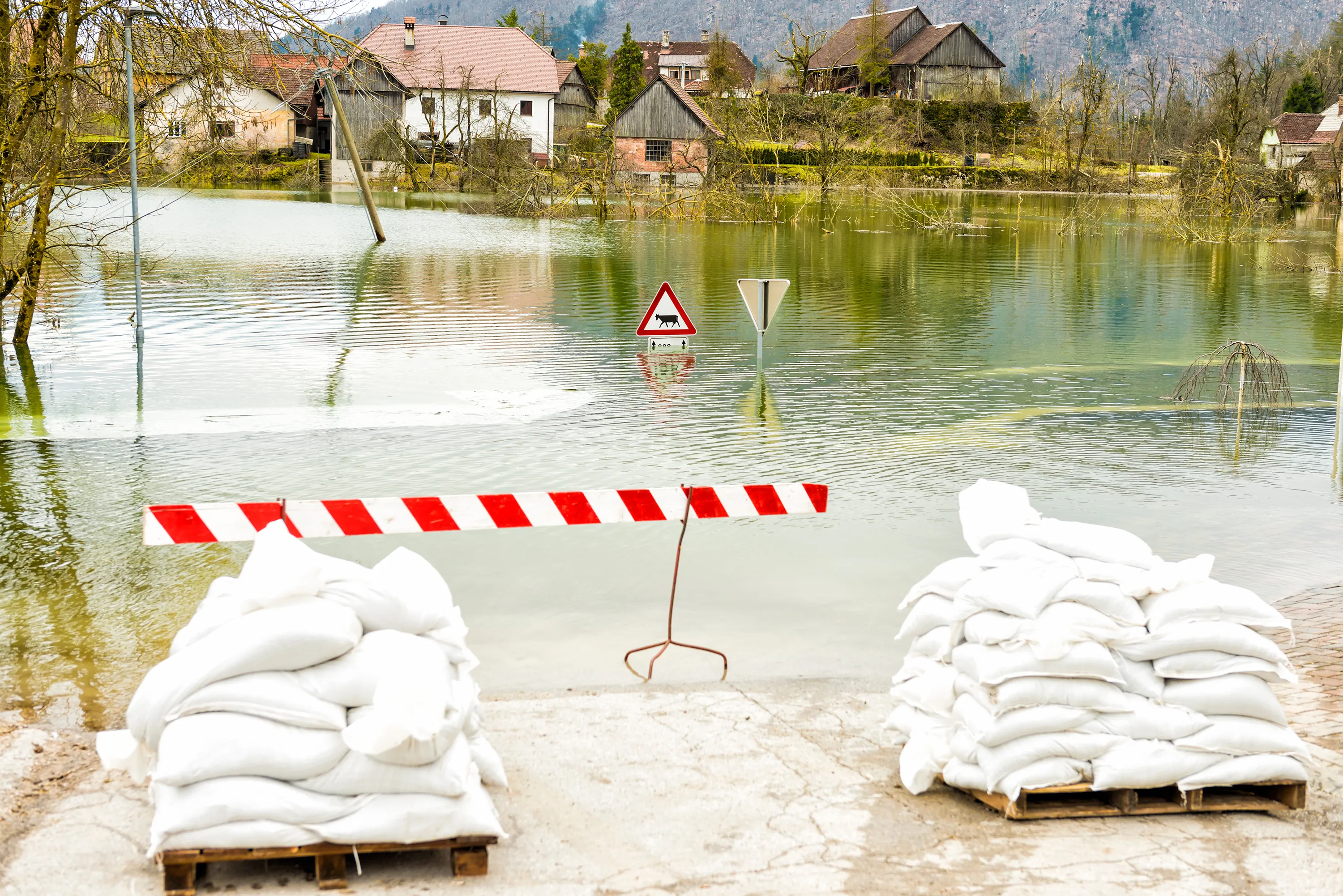 Aufgestappelte Sandsäcke liegen am Ufer eines vom Hochwasser betroffenen Flusses