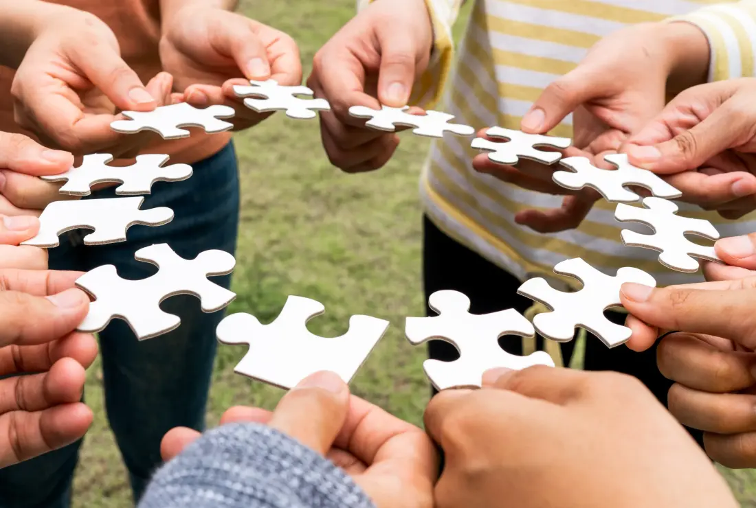 Menschen halten Puzzleteile in den Händen und bilden damit einen Kreis